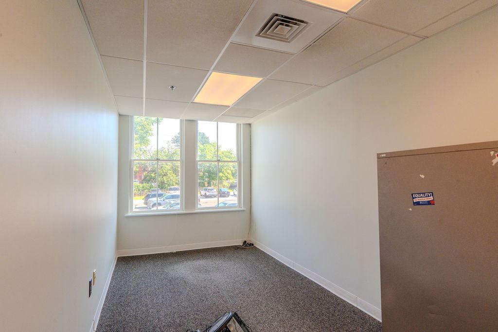 Office with white walls, gray carpet, and large windows.